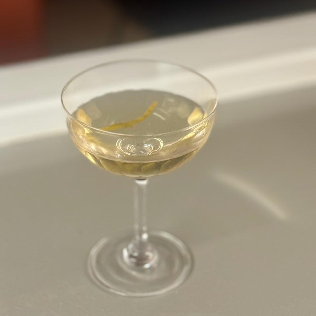 A samphire martini, golden in hue and garnished with a samphire sprig.