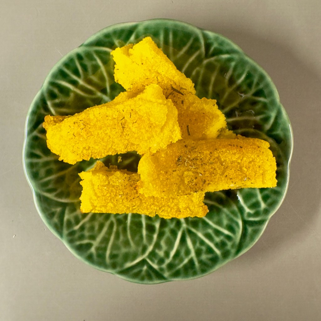 A plate of thick polenta chips dusted with rosemary salt.